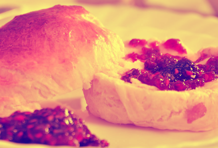 A picture of a scone, thickly spread with jam.